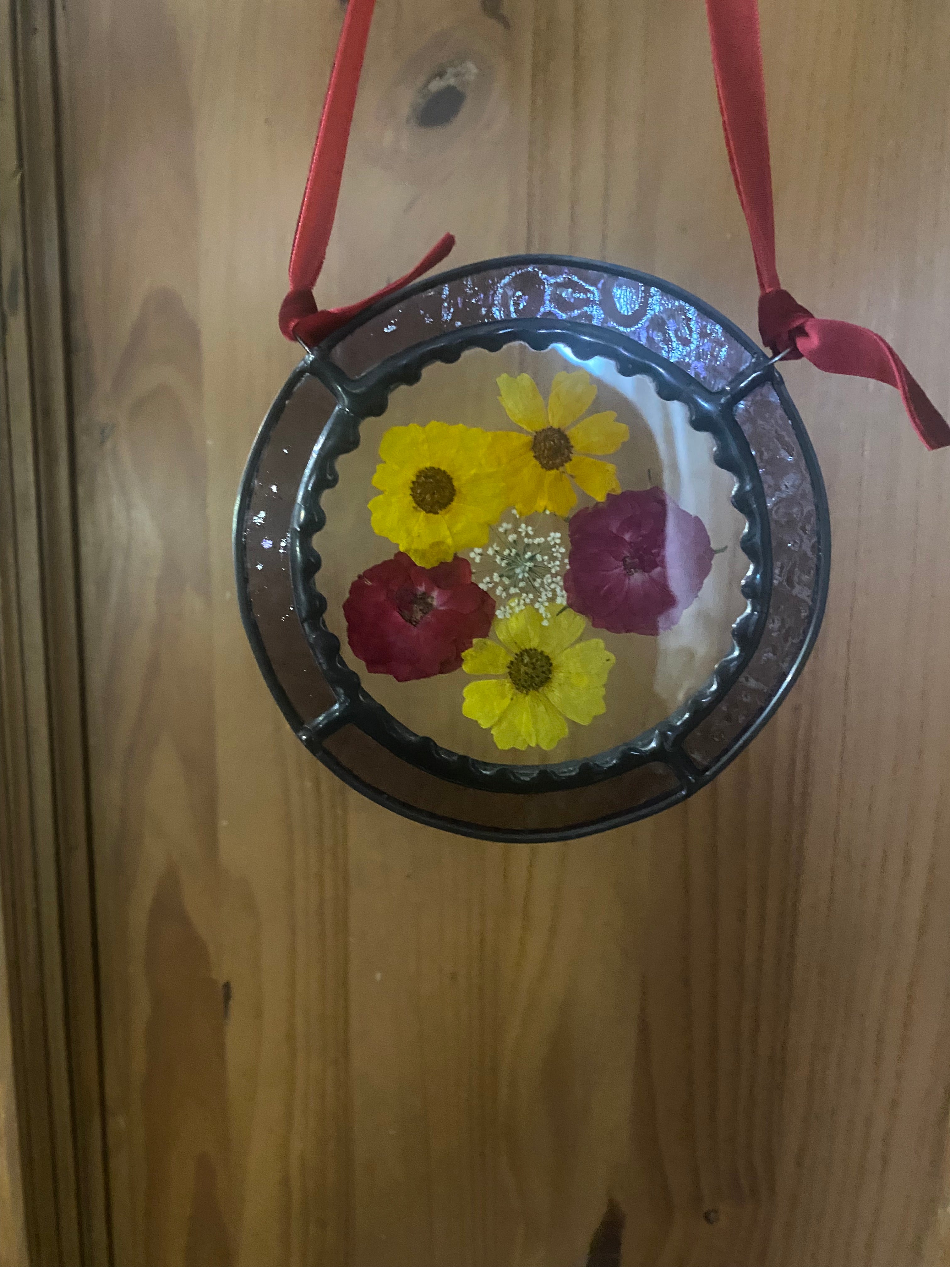 yellow and red dried flowers in a purple stained glass frame
