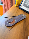 A purple and pink incense stick holder with an iridescent moon