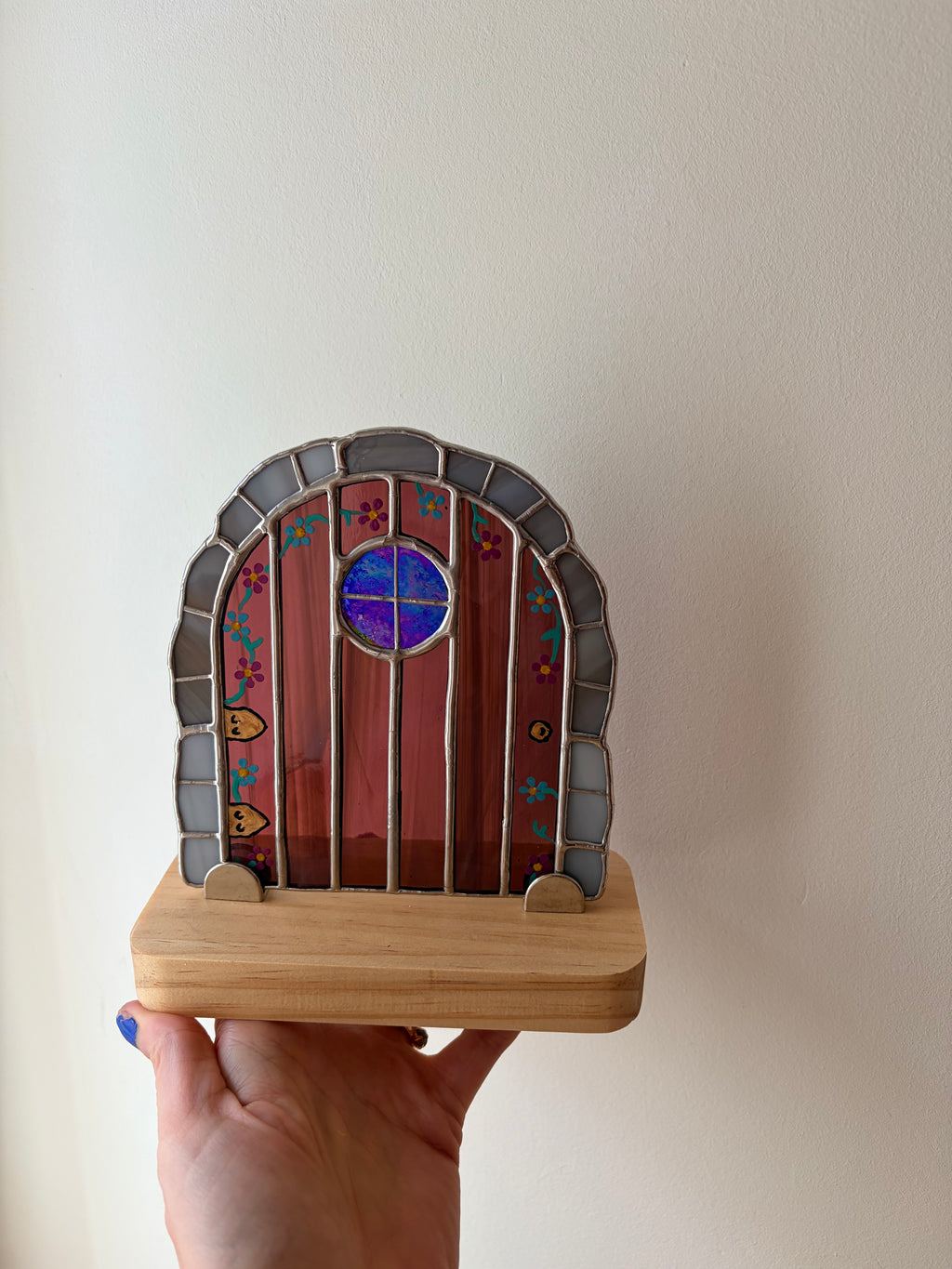 Stained glass fairy door held against a plain background