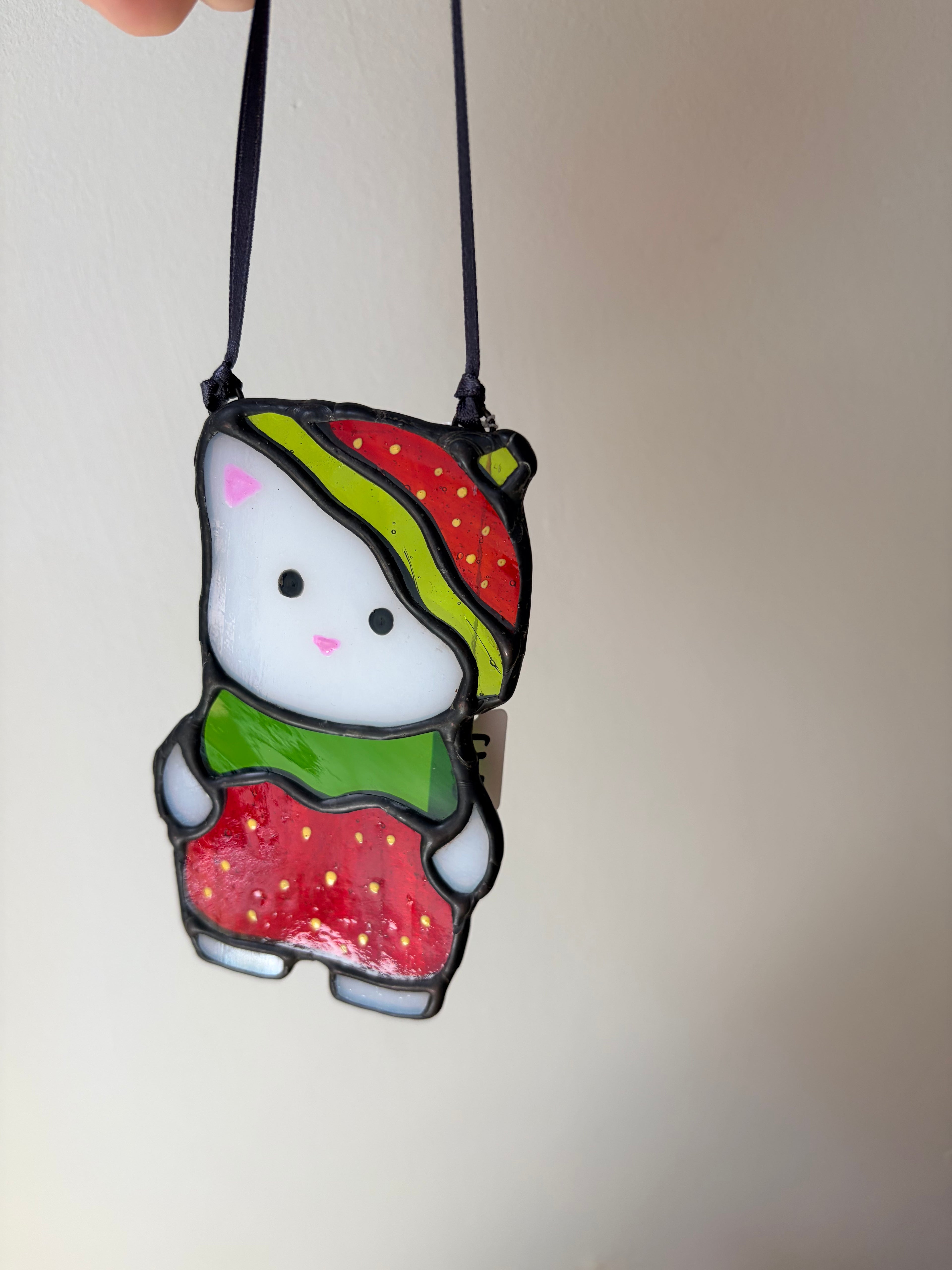 Stained glass cat dressed as a strawberry reminiscent of sylvanian families