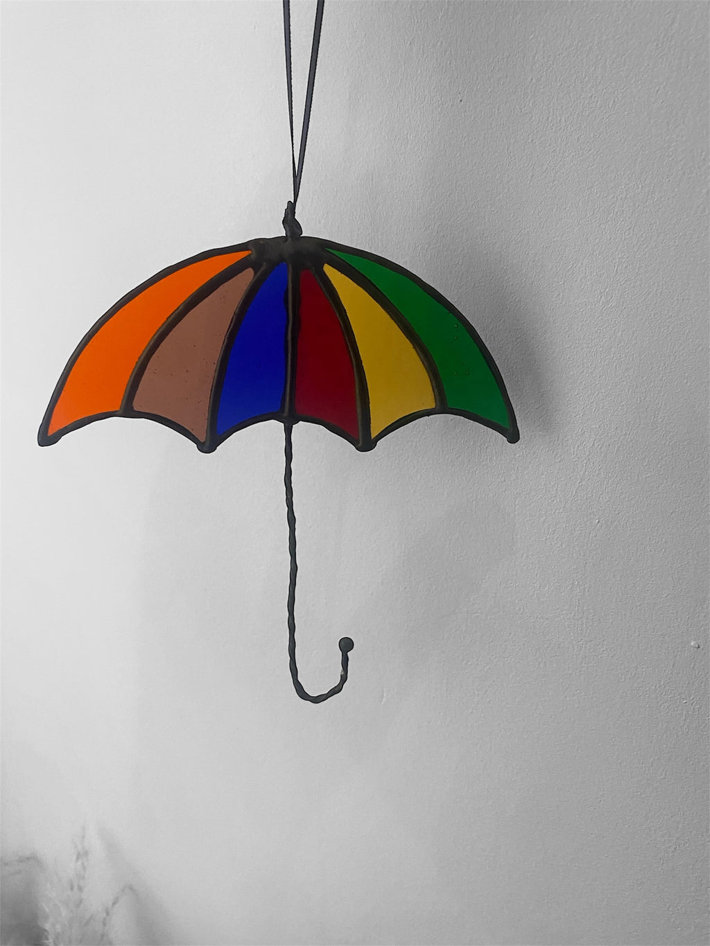 Colorful stained glass umbrella hanging against a plain background