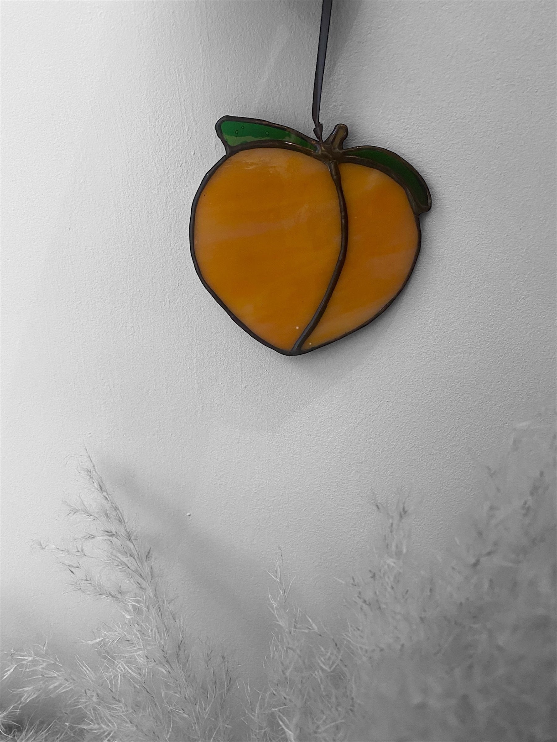 Stained glass peach ornament on a white background