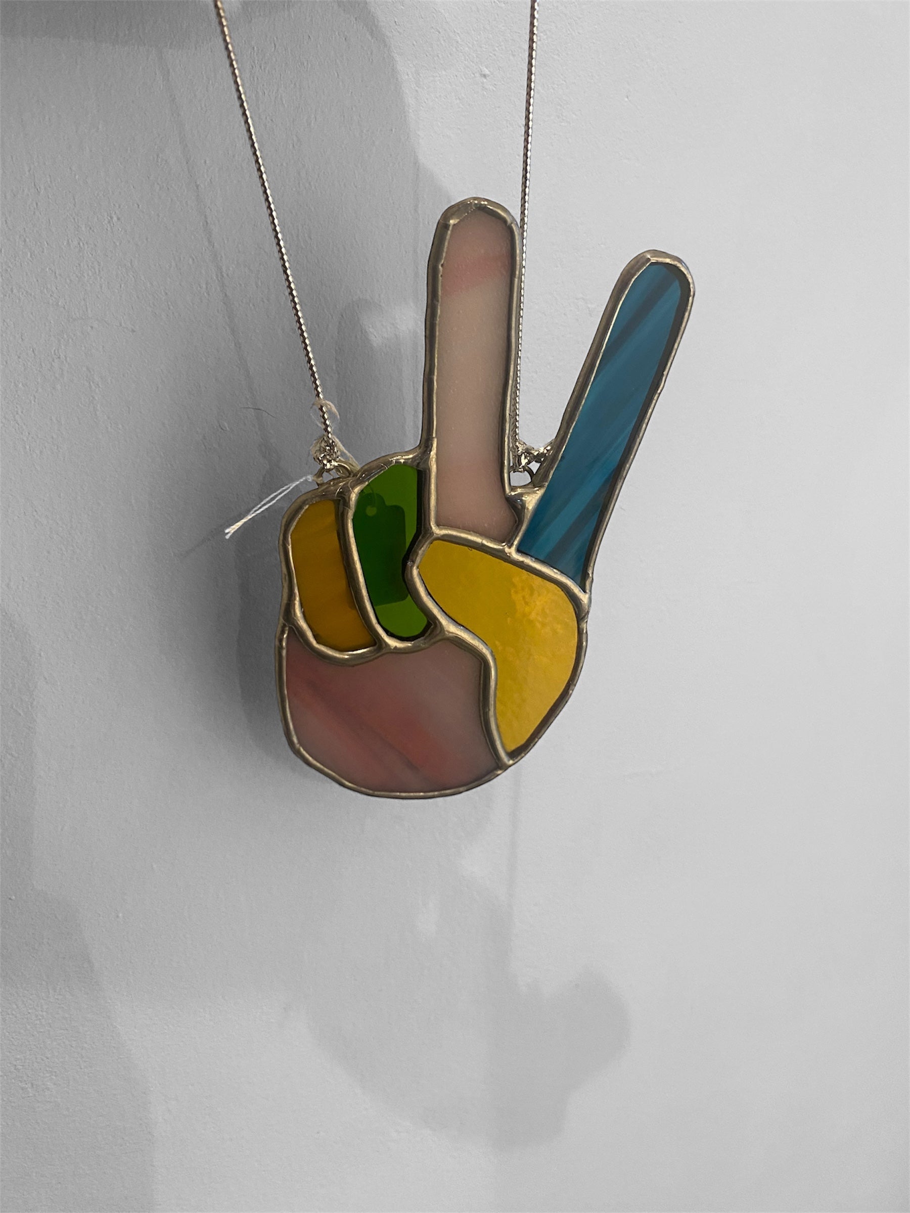Colorful peace sign pendant on a chain against a white background