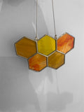 Hexagonal stained glass panel with orange and yellow colors on a plain background