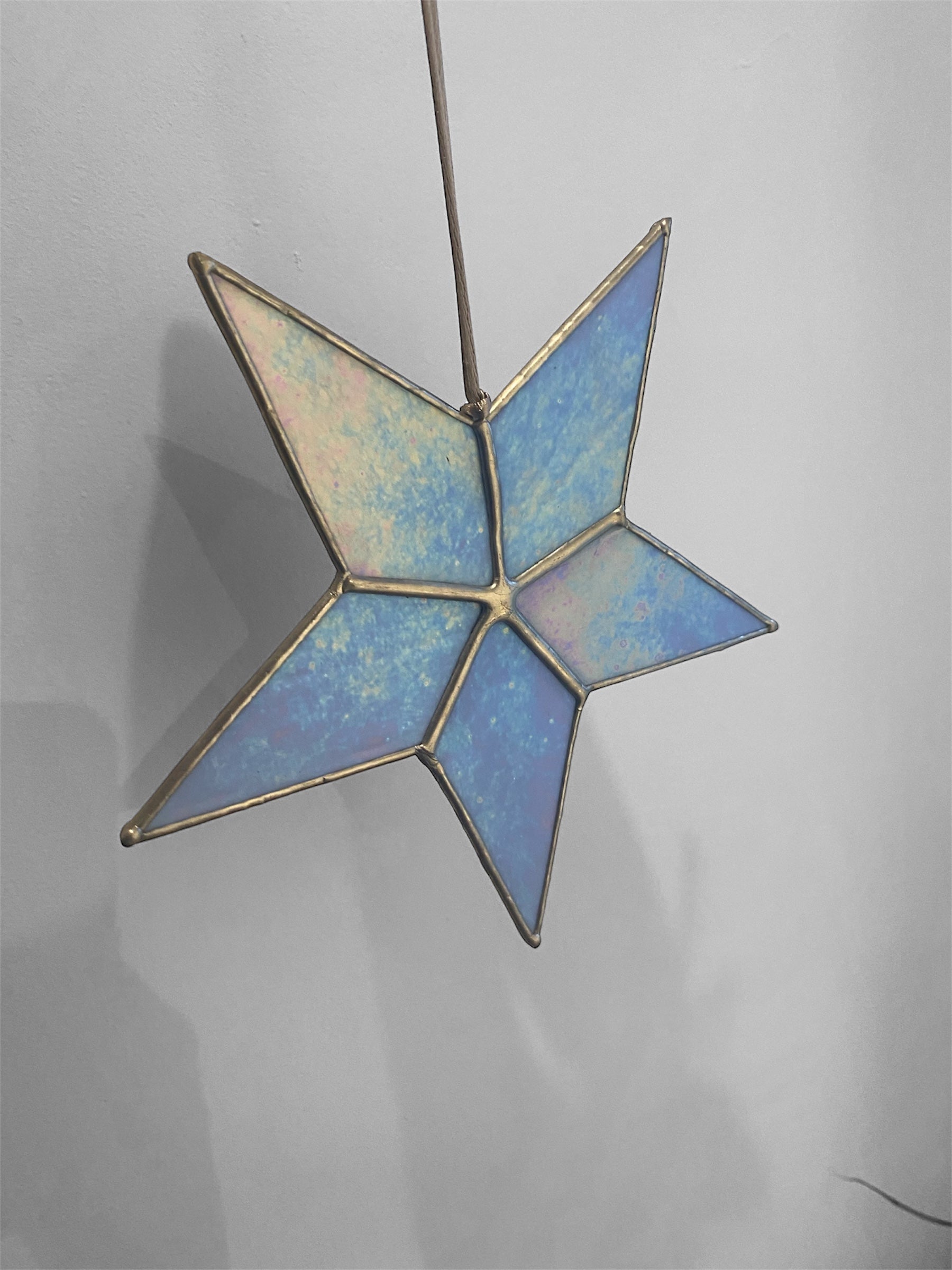Star-shaped stained glass ornament on a plain background showing iridescence