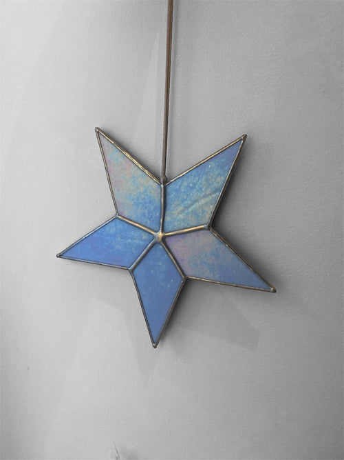 Blue stained glass star hanging on a plain background