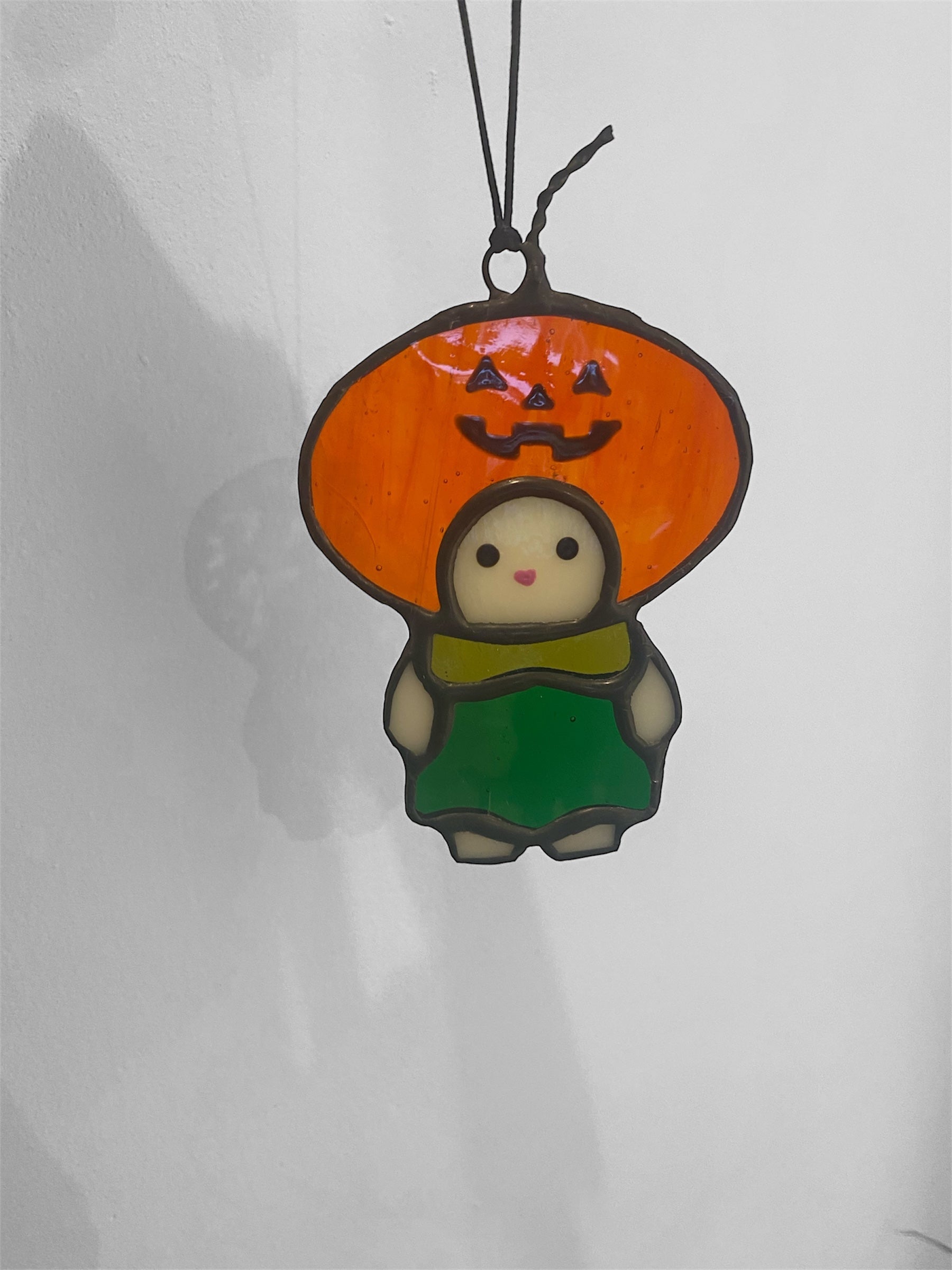 Kawaii-style cat or rabbit character with a pumpkin costumer ornament on a gray background