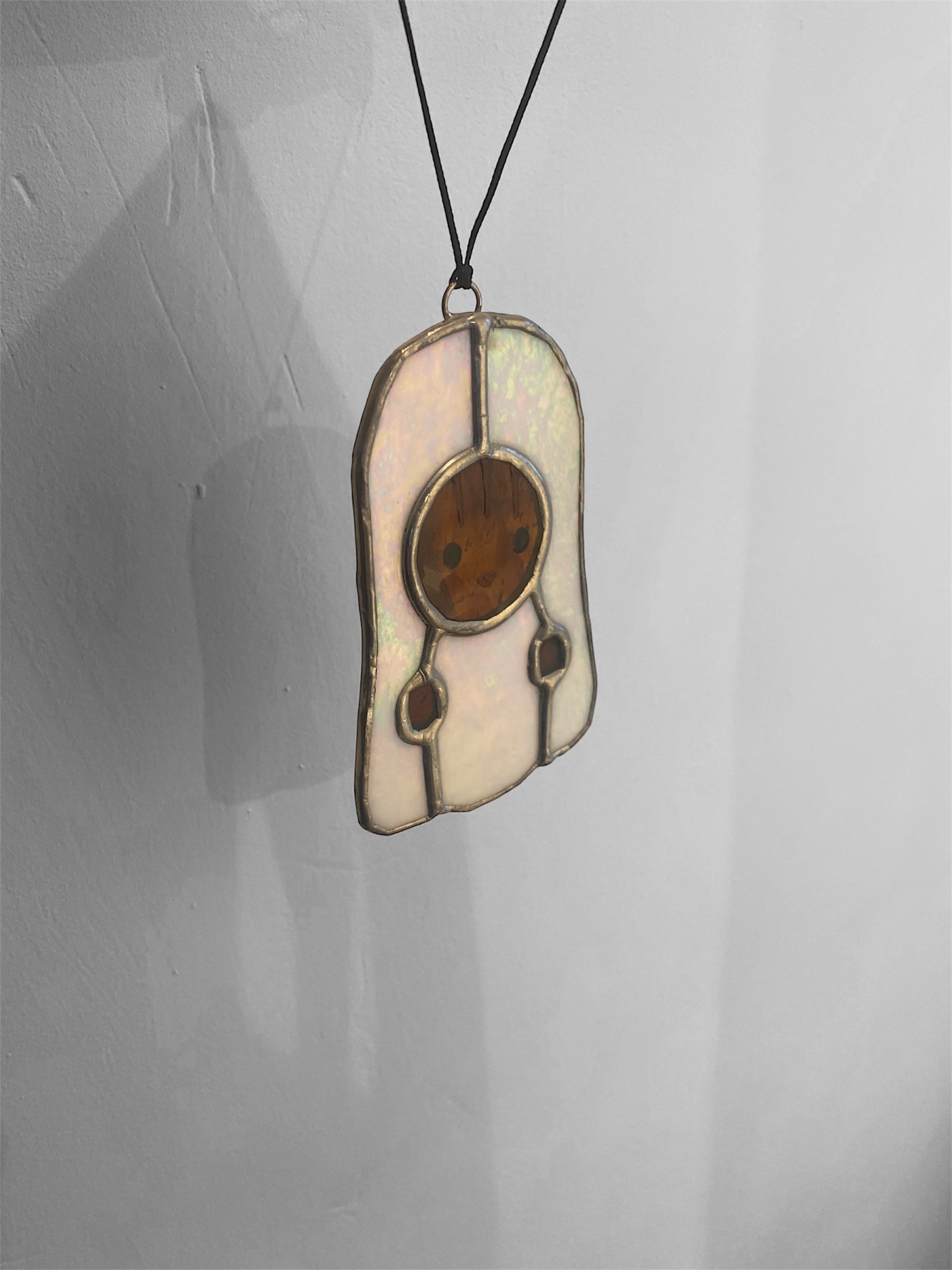 Kawaii-style squirrel character with a ghost costume stained glass ornament on a grey background shining rainbow colours in the light