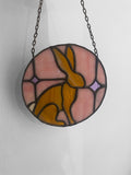 Stained glass window hanging with a rabbit design on a white background