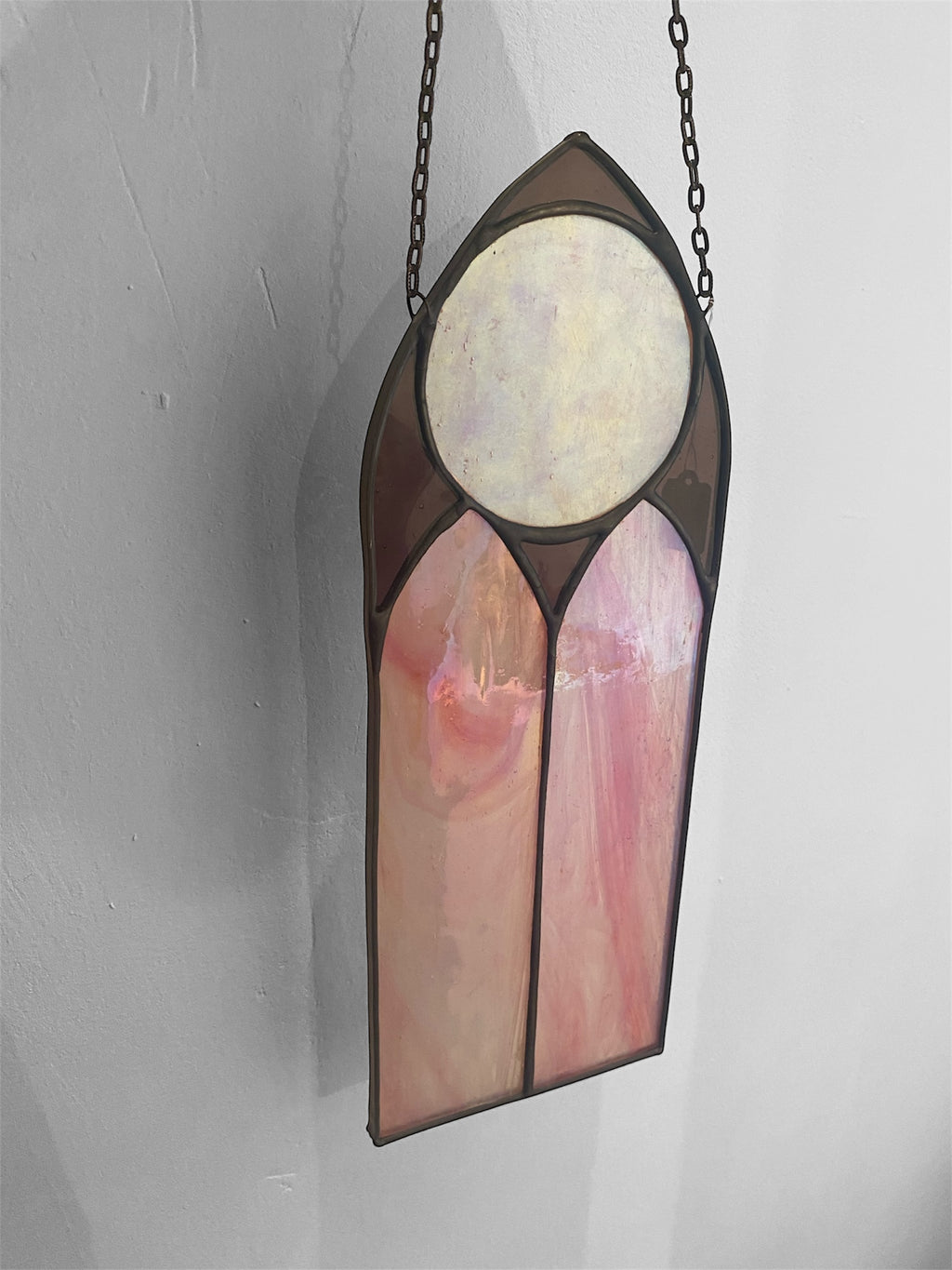 Stained glass panel with pink and white design on a gray background