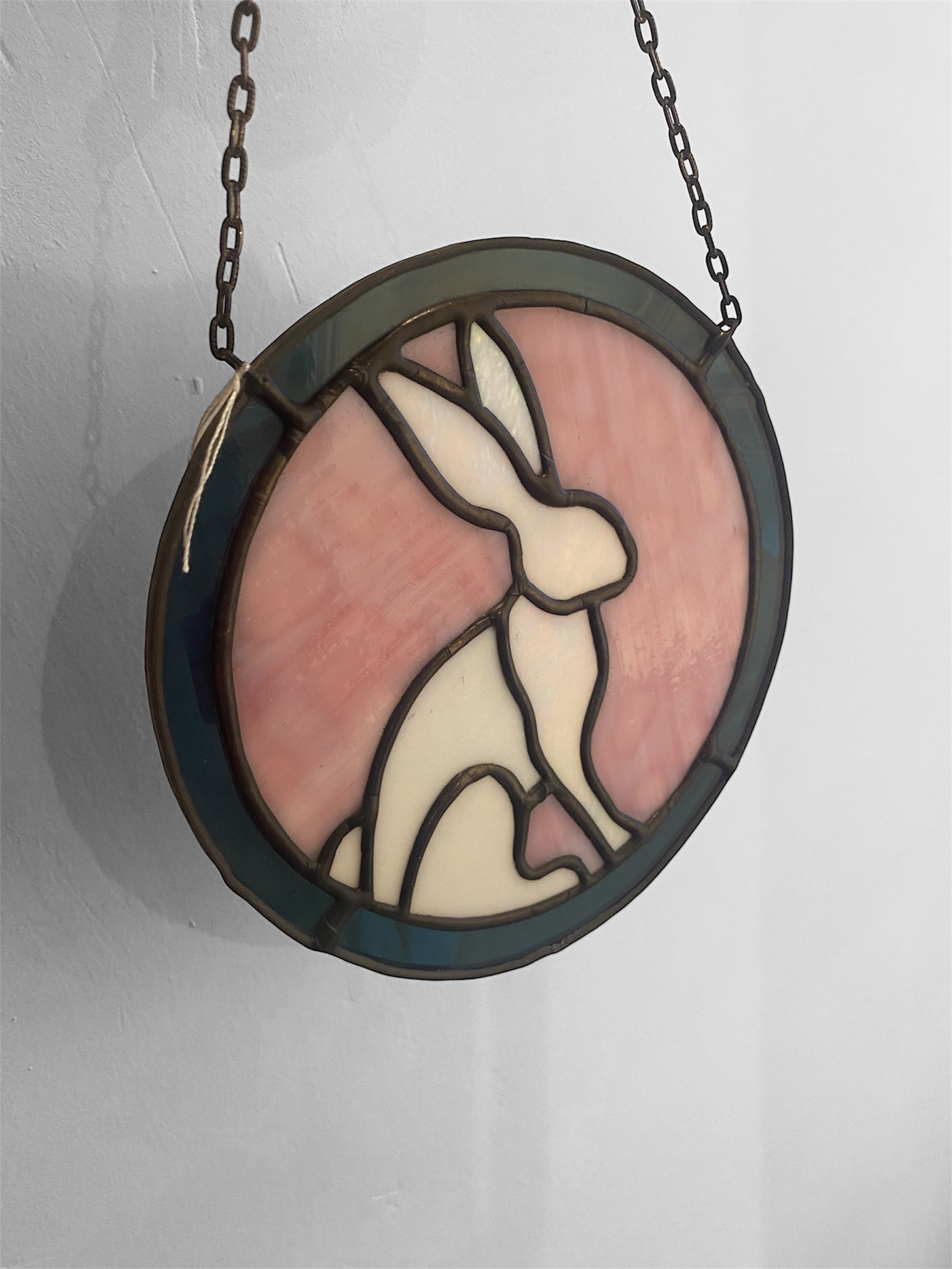 Stained glass window with a rabbit design on a plain background
