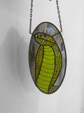 Stained glass panel with a green snake design on a white background