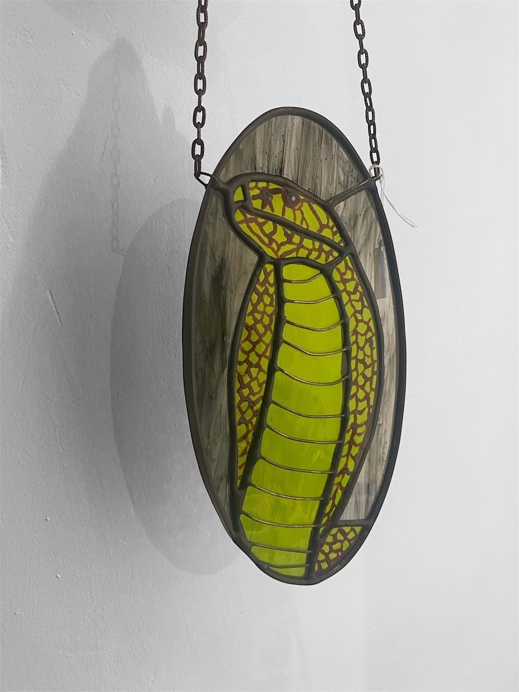 Stained glass panel with a green snake design on a white background