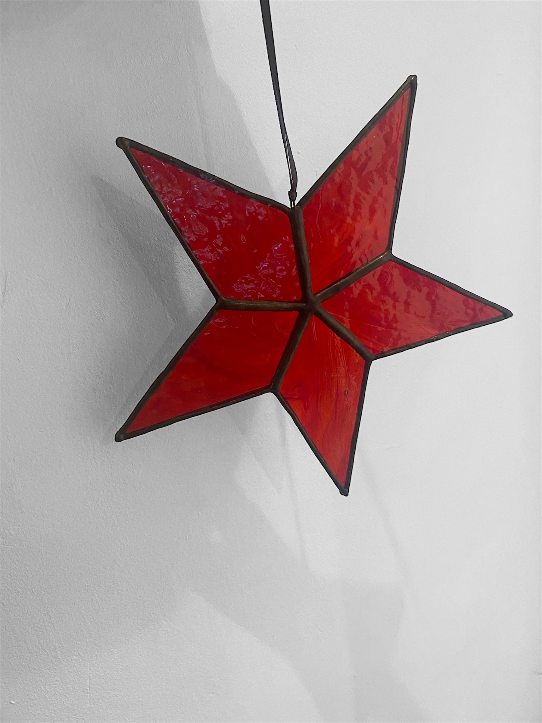 Red star-shaped stained glass hanging on a white background