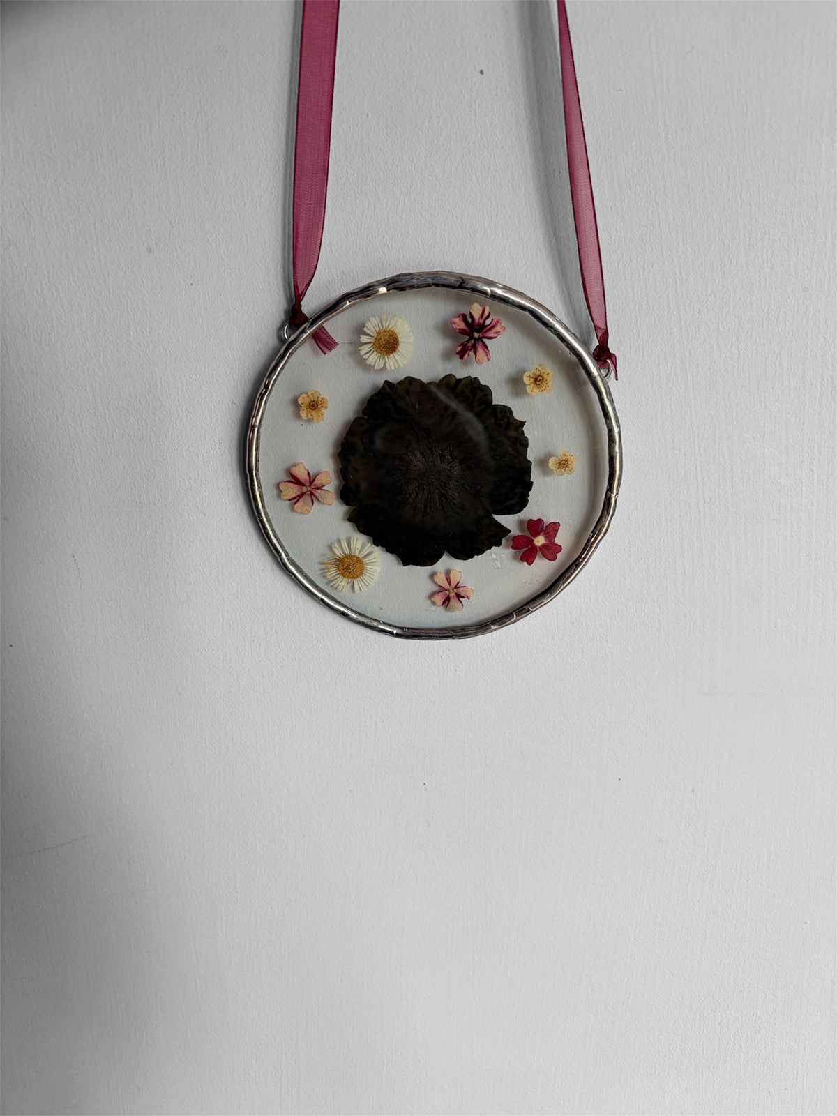 Glass hanging ornament containing dried flowers