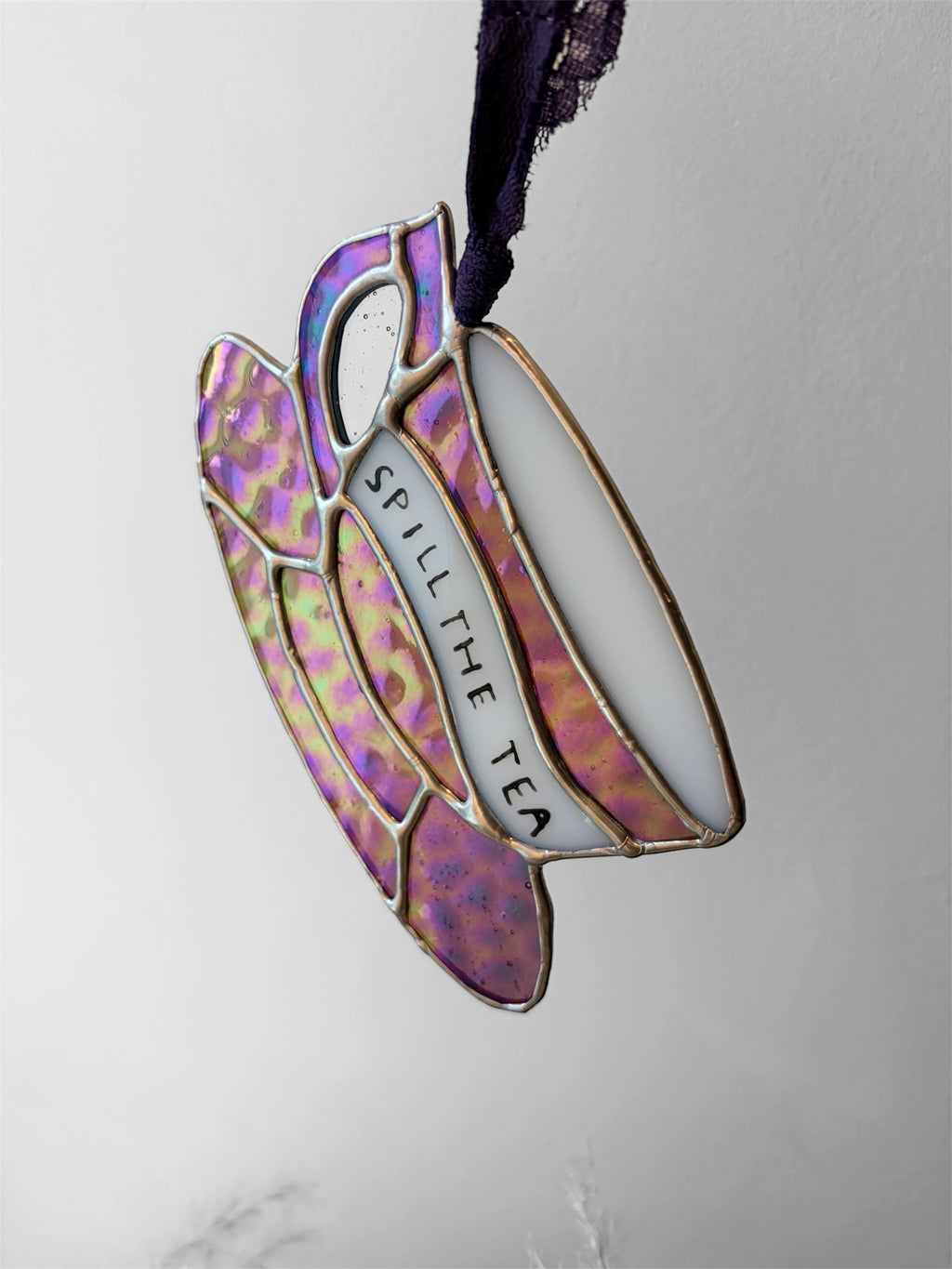A purple iridescent glass teacup with a funny phrase painted on the side