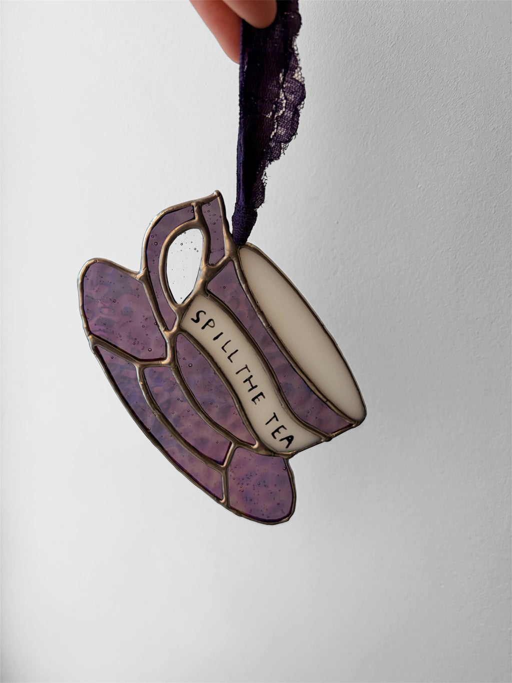 A pink iridescent glass teacup with a funny phrase painted on the side