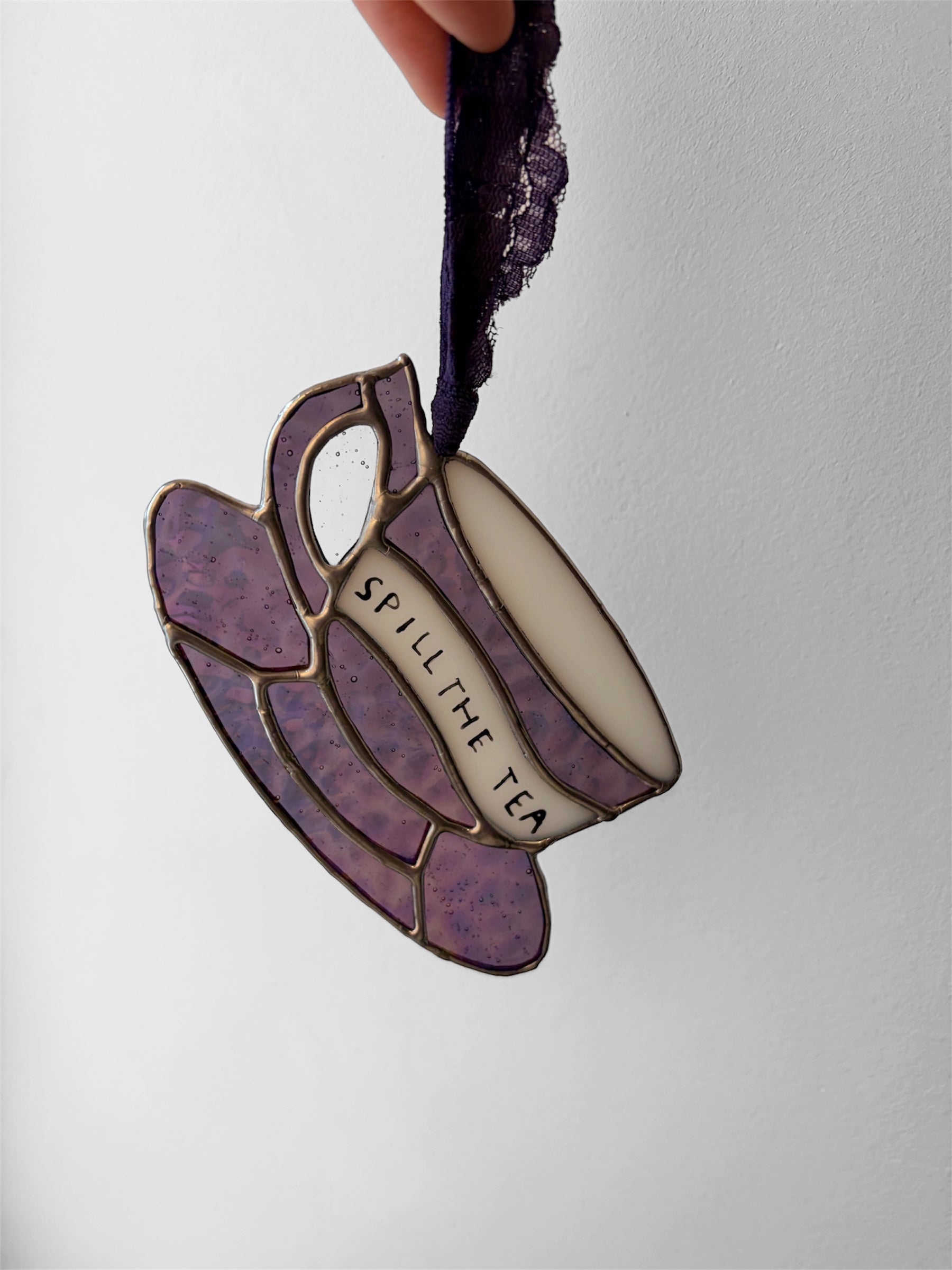 A pink iridescent glass teacup with a funny phrase painted on the side