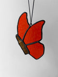 Stained glass butterfly made with orange glass, with a bullet instead of a butterfly body