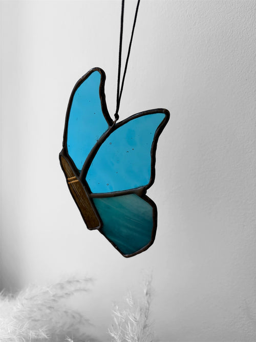 A blue stained glass butterfly with a bullet instead of a butterfly body