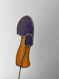 Decorative item resembling a mushroom on a stick with purple cap and orange stem against a gray background