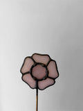 Decorative glass flower on a stick against a plain background
