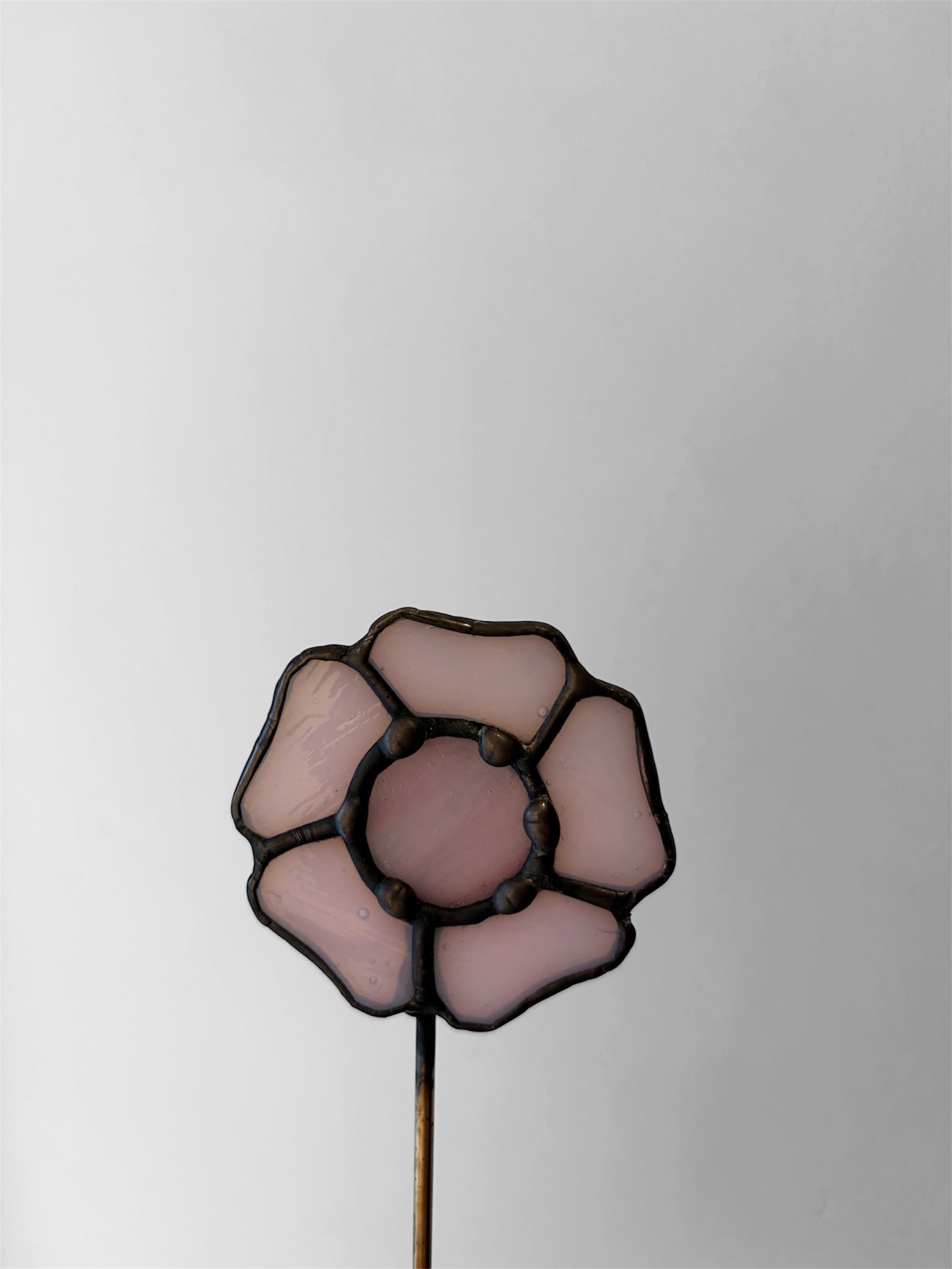 Decorative glass flower on a stick against a plain background