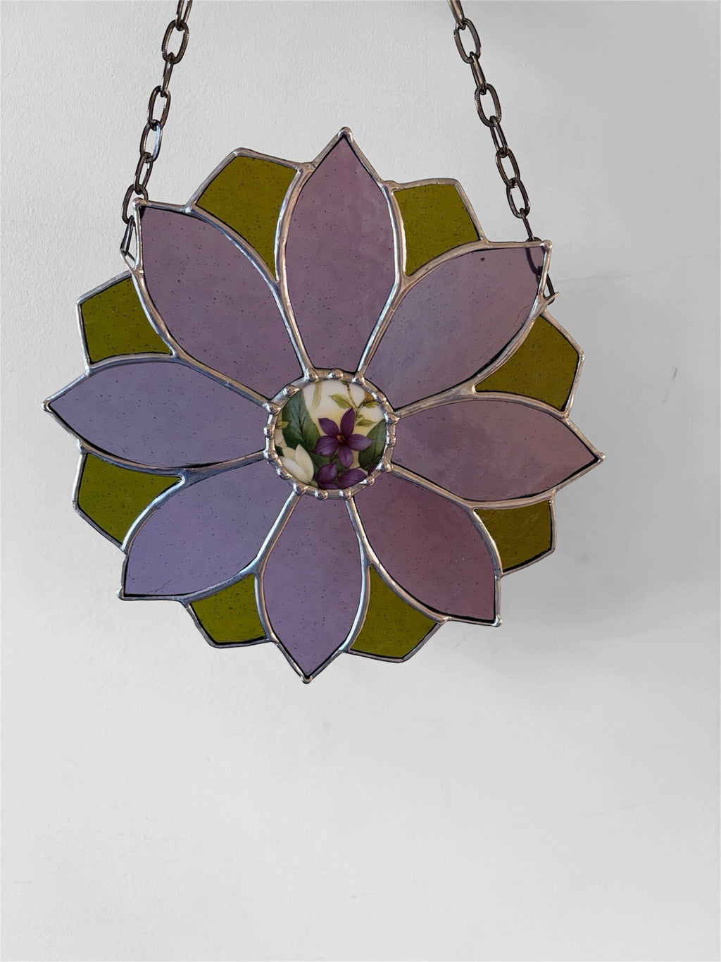 Stained glass flower hanging on a chain against a white background