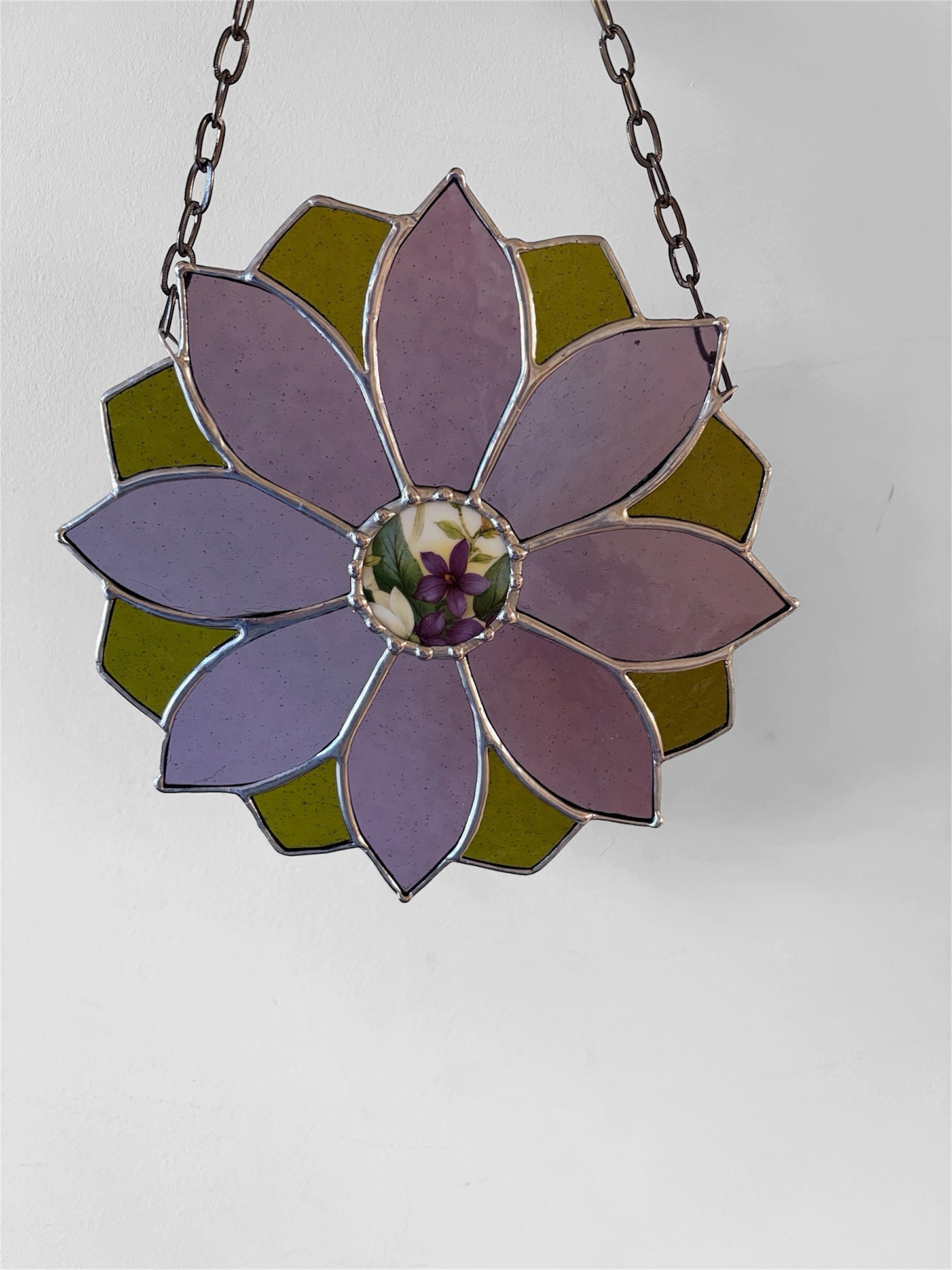 Stained glass flower hanging on a chain against a white background