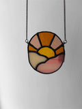 Stained glass pendant with a chain on a plain background