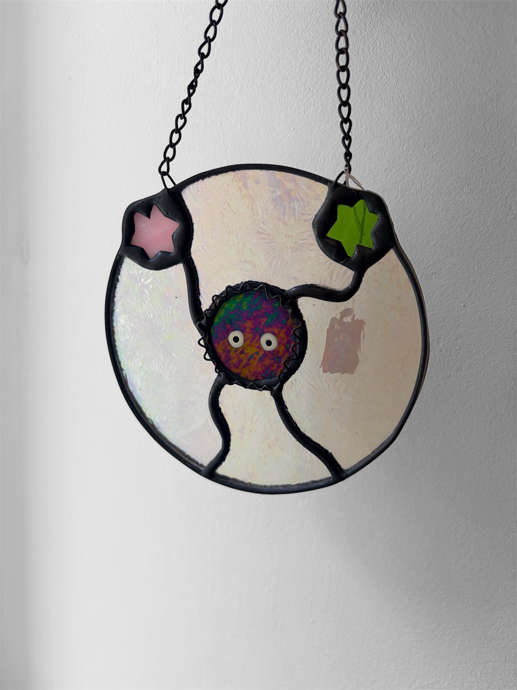 Stained glass piece with a colorful character design on a plain background