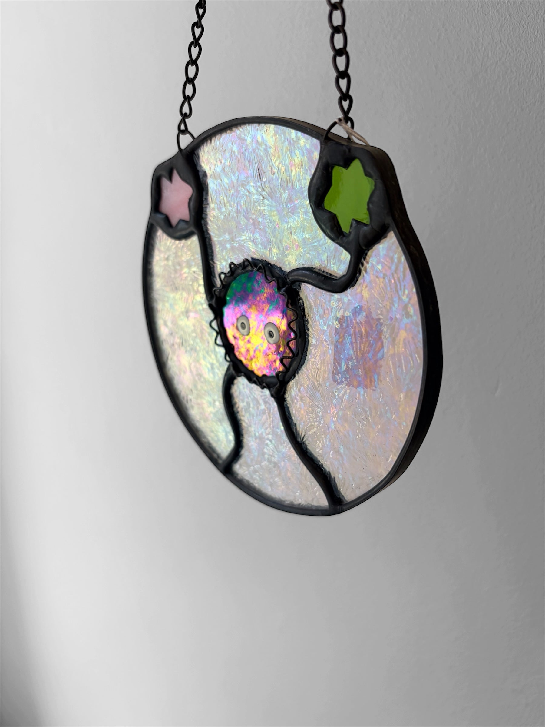 Stained glass pendant with celestial design on a gray background