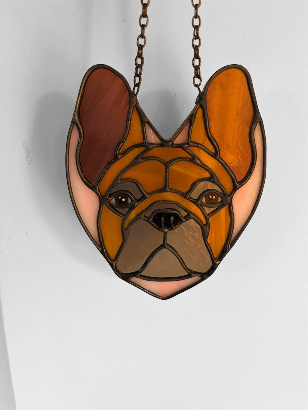 Stained glass pendant of a dog's face on a white background