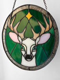 A stained glass panel picturing a white stag under a star, against a green and silver background