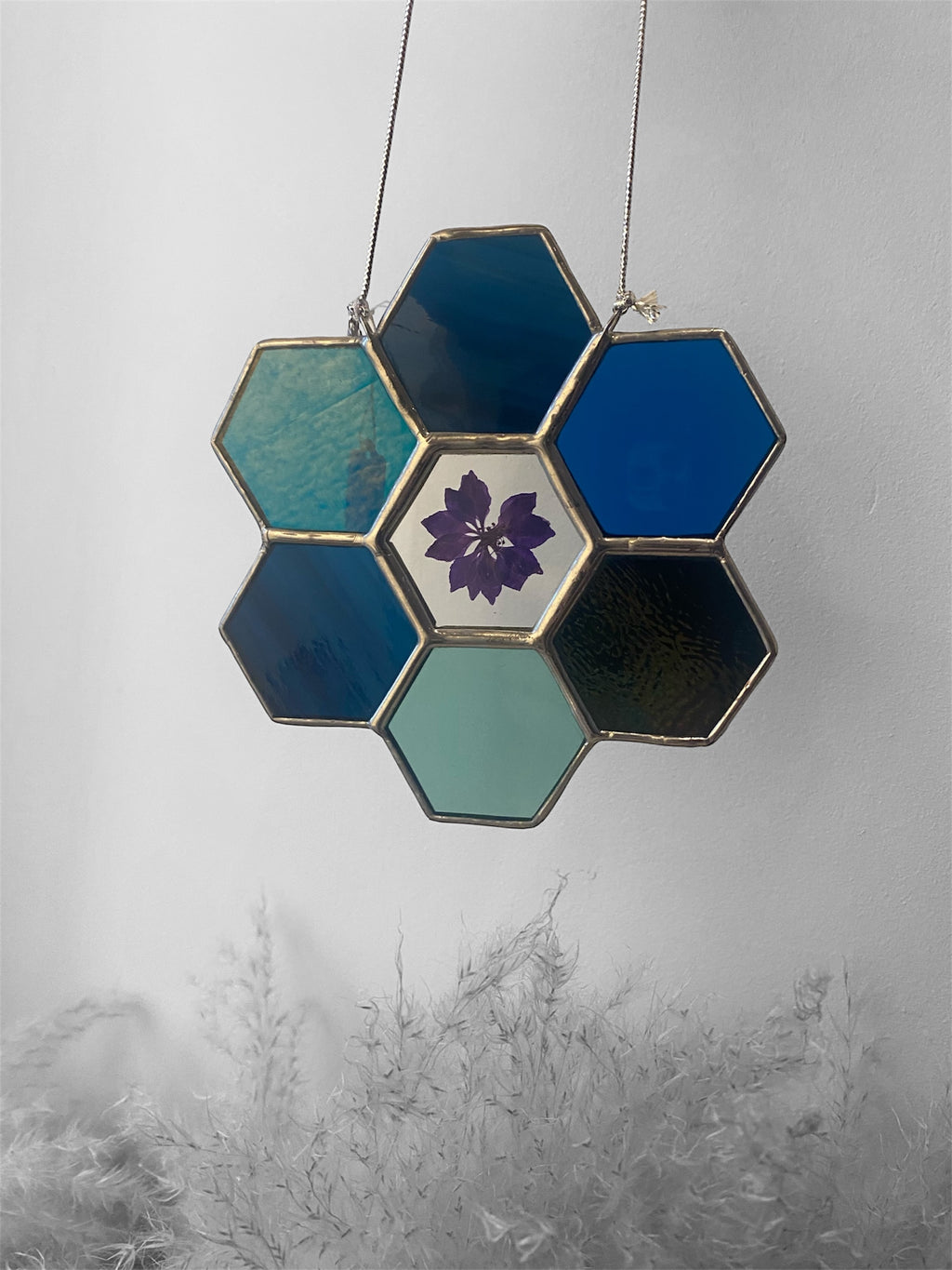 Hexagonal stained glass panel with a floral design on a gray background