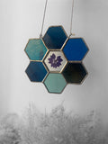 Hexagonal stained glass panel with a floral design on a gray background