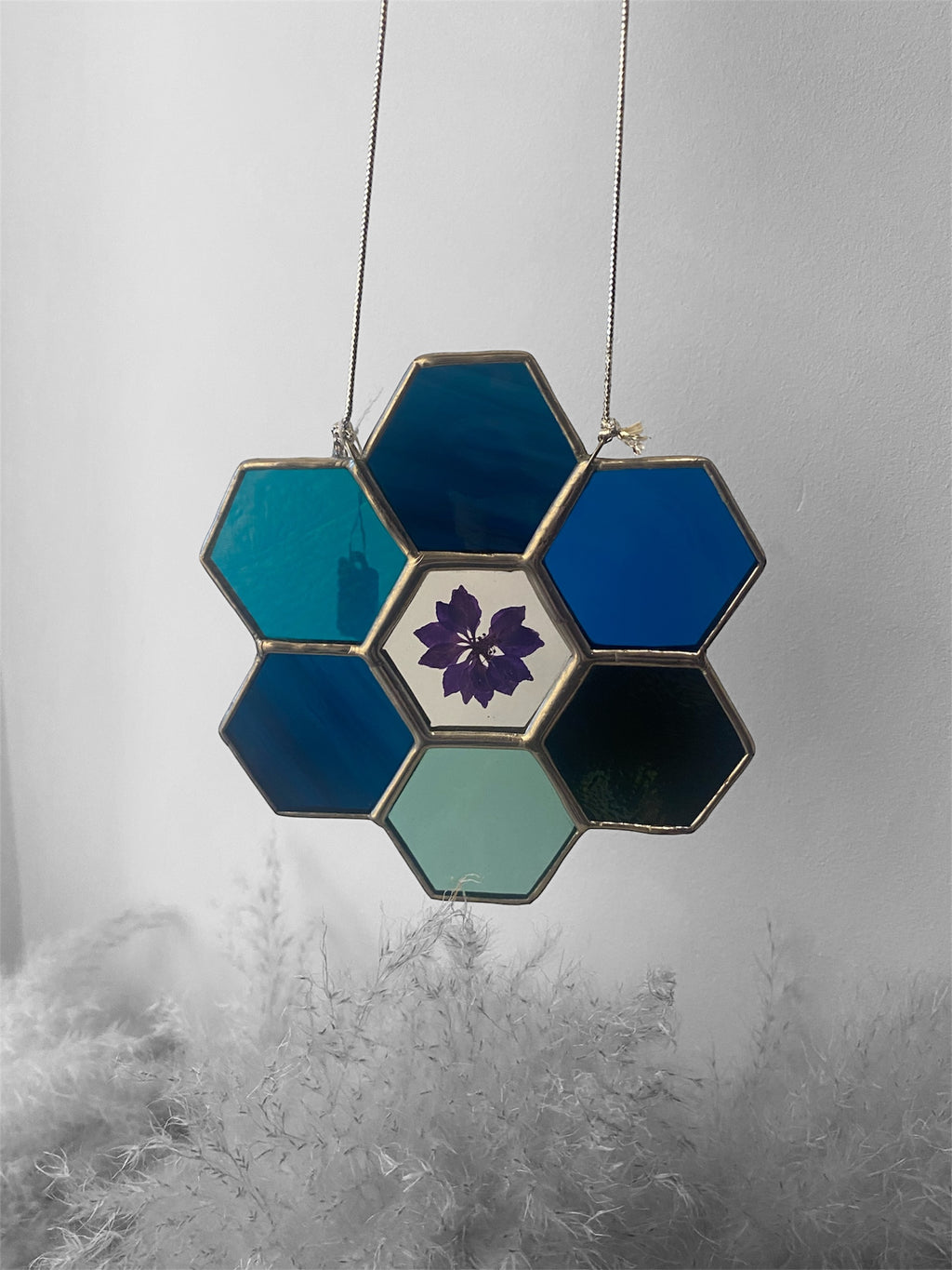 Hexagonal stained glass panel with floral design on a textured gray background