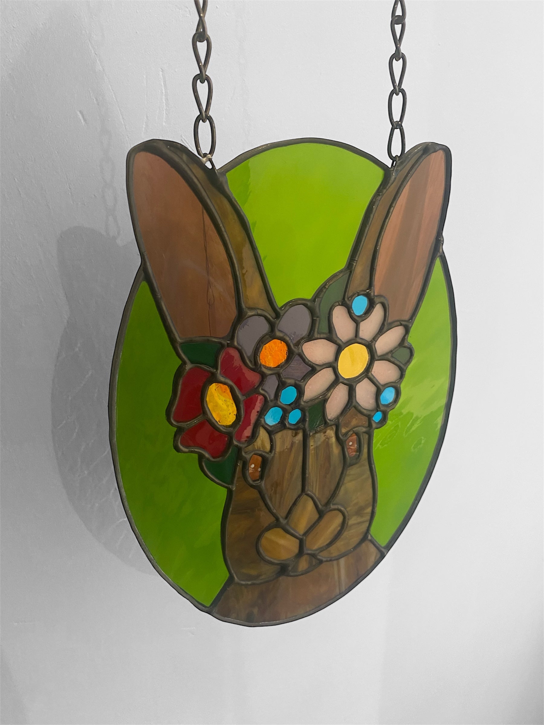 Stained glass window hanging of a rabbit or hare with a flower crown on a white background