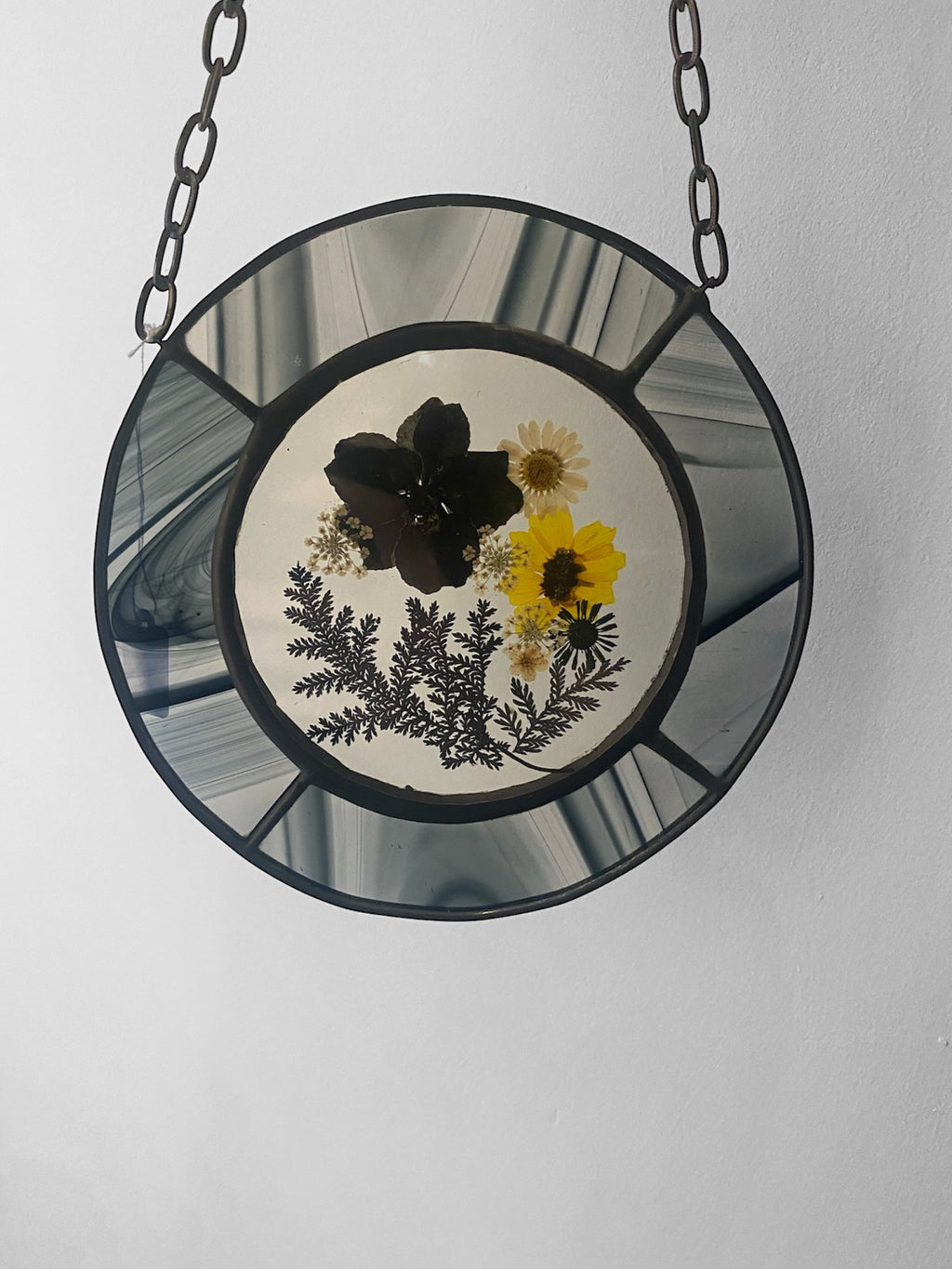 Black and yellow dried flowers framed in black streaky glass