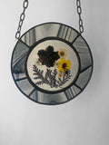 Black and yellow dried flowers framed in black streaky glass