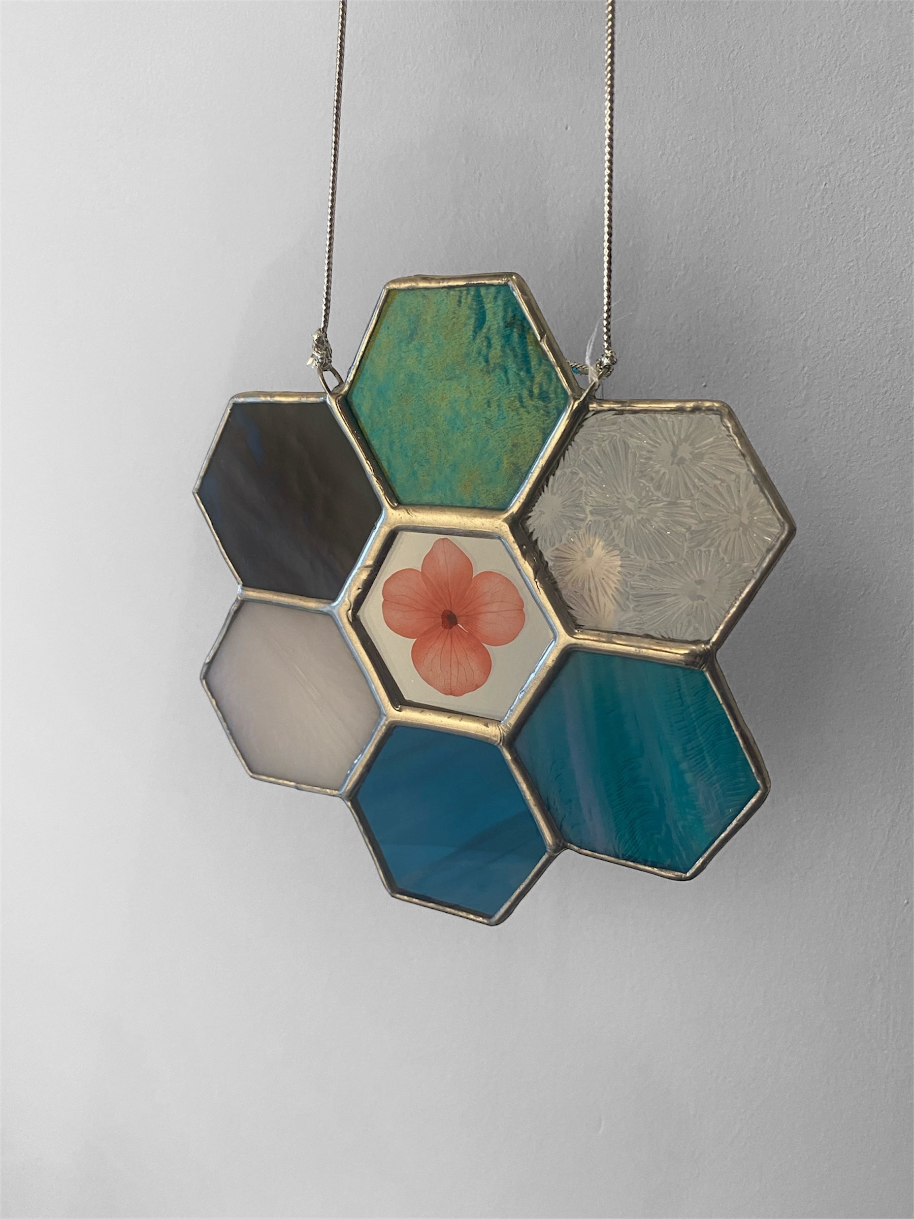 Hexagonal stained glass panel with floral design on a plain background