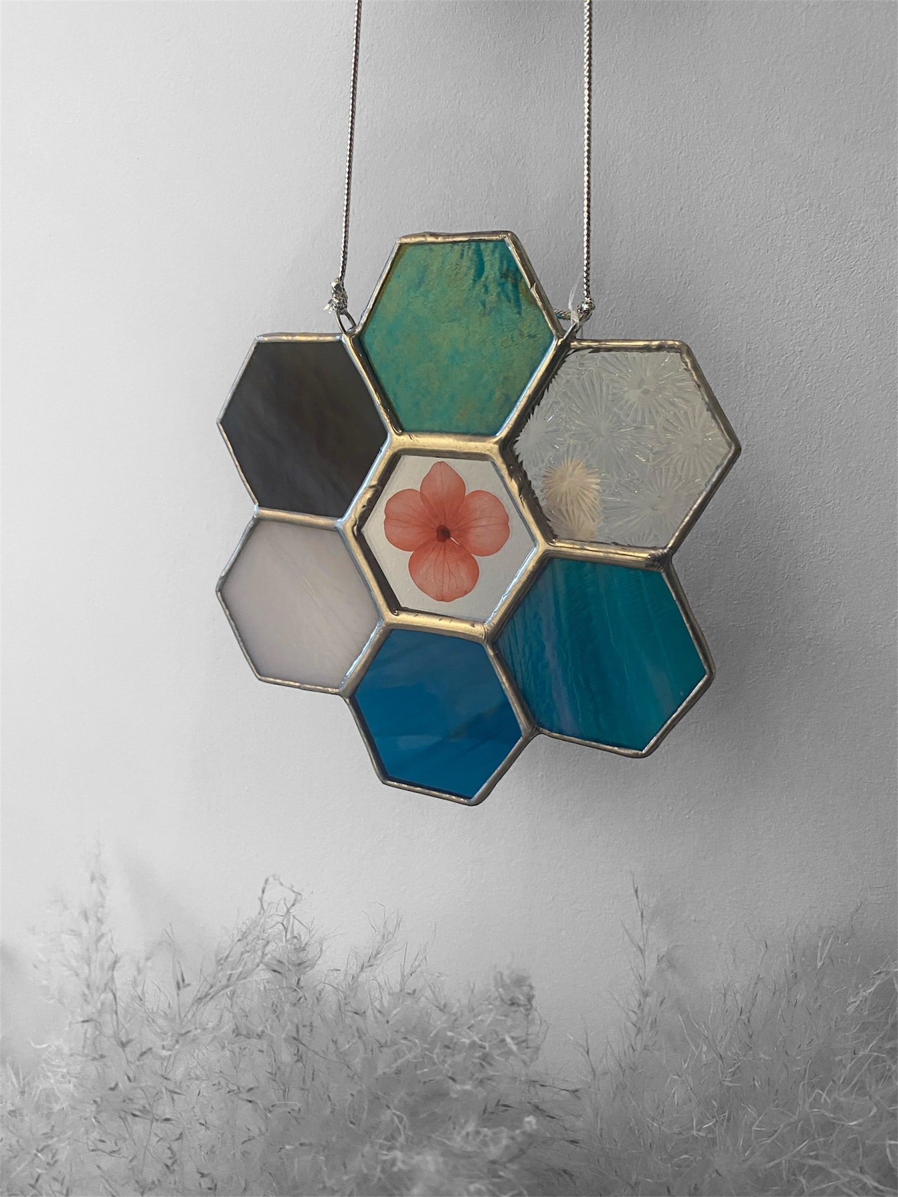 Hexagonal stained glass panel with floral dried hydrangea on a gray background